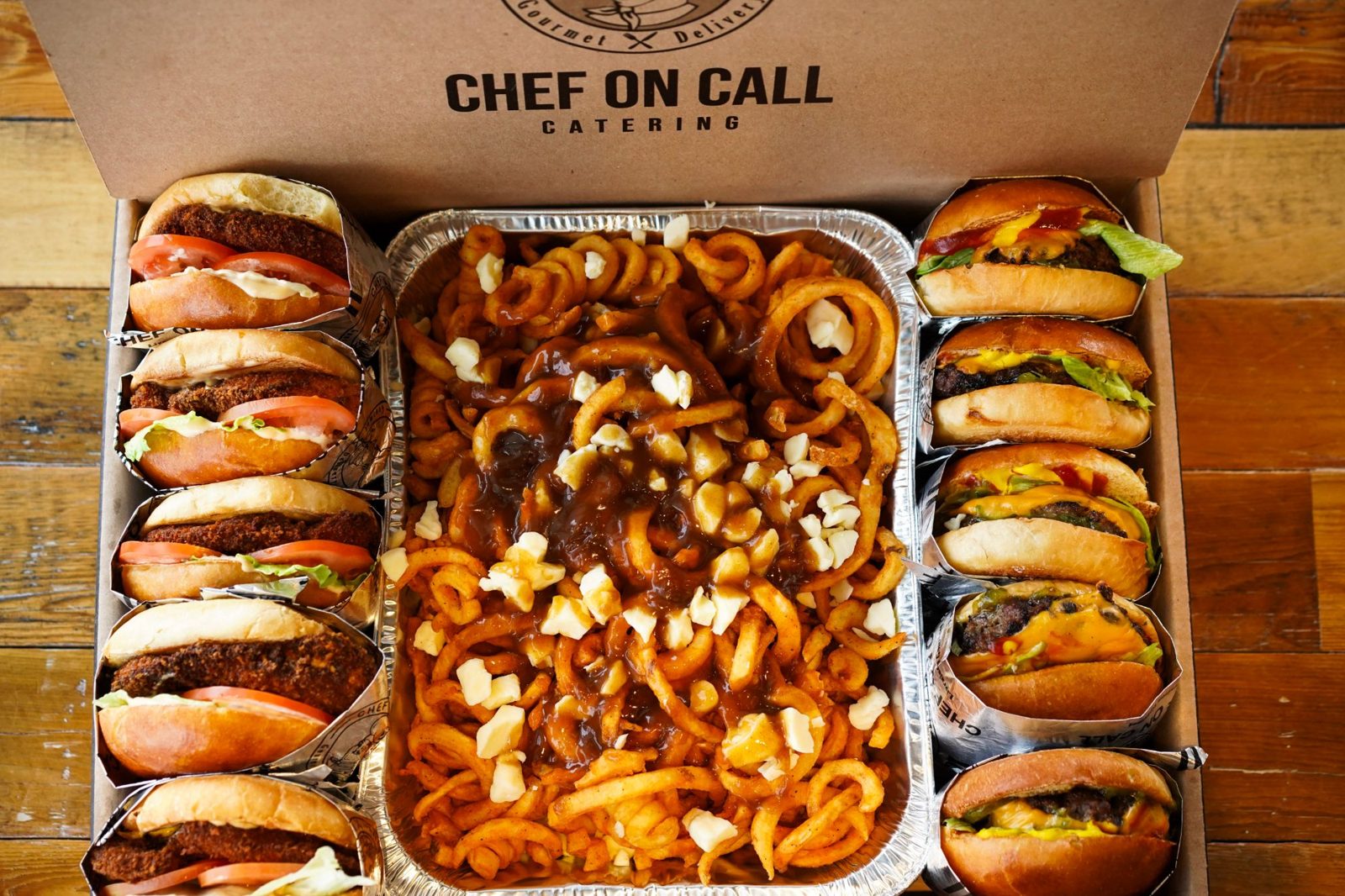 Chef On Call catering box with gourmet burgers, chicken sandwiches and a tray of curly fry poutine
