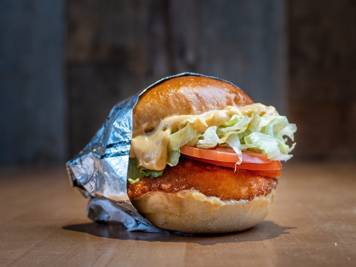 The Oh So Crispy Burger, a hand breaded halal crispy chicken patty with lettuce and tomato on an Ace Bakery brioche bun