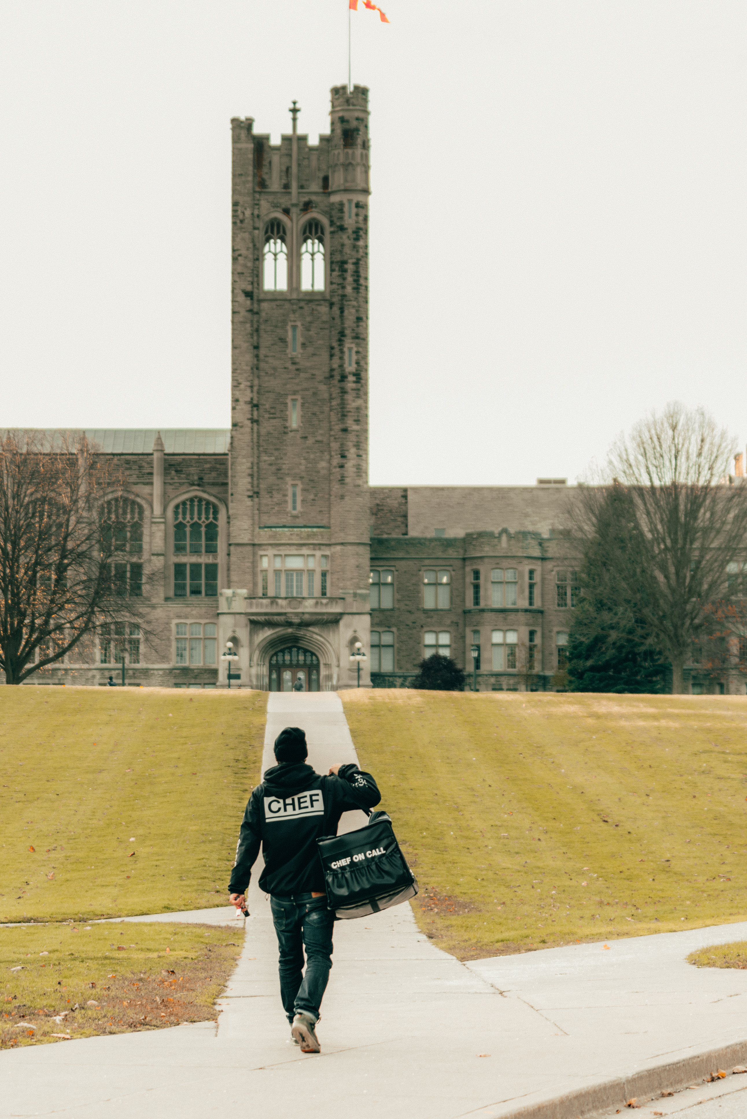 Chef On Call delivery driver walking toward Western University with a branded insulated bag